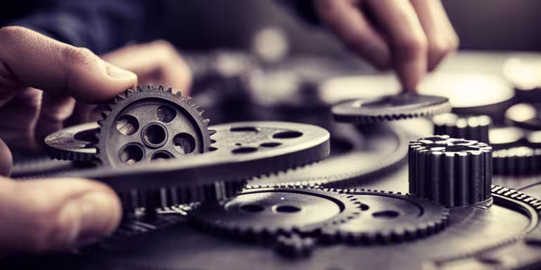 Multiple gears being placed together by two hands